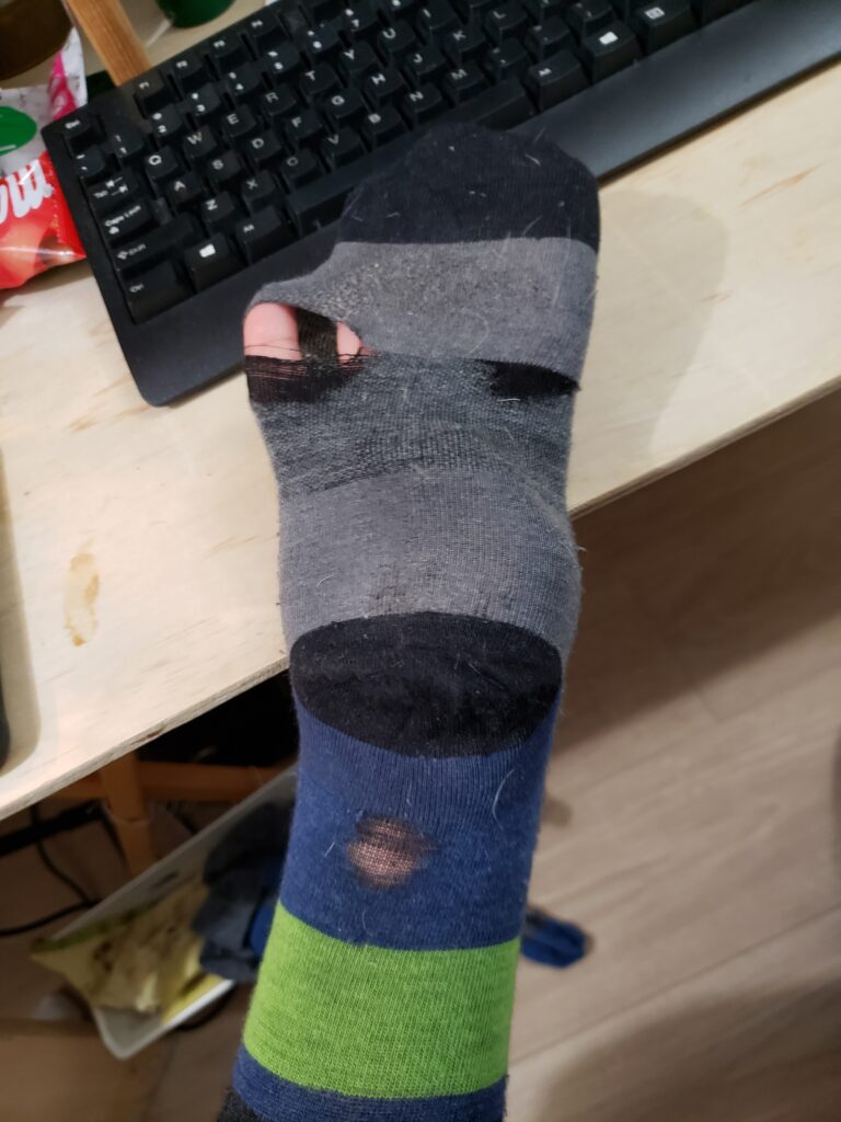 Darn Tough Sock with holes. Green and Blue on the leg part.